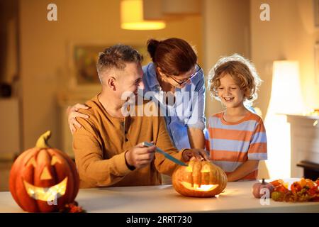 Famille avec enfants sculptant la citrouille. Halloween Trick ou friandise. Parents et enfants décorant la maison. Mère, père et petit garçon sculptent la lanterne. Banque D'Images