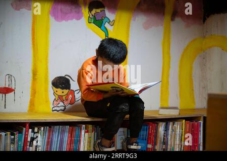 230707 -- GONGSHAN, le 7 juillet 2023 -- Un enfant lit un livre à la bibliothèque de Banshan Huayu dans le village de Qiunatong, dans le canton de Bingzhongluo, dans le comté autonome de Gongshan Dulong et nu, préfecture autonome de Lisu de Nujiang, province du Yunnan dans le sud-ouest de la Chine, le 5 juillet 2023. La rivière Nujiang, descendant des montagnes Tanggula sur le plateau Qinghai-Tibet, se fraie un chemin à travers les majestueuses montagnes du Yunnan où se forme un magnifique canyon. Niché à la pointe nord du canyon de la rivière Nujiang se trouve le village de Qiunatong, qui abrite une bibliothèque unique appelée Banshan Huayu Half Hill Flow Banque D'Images