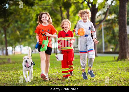 Les enfants se déguent en costume d'Halloween. Les enfants de couleur s'habillent avec un seau à bonbons dans la rue de banlieue. Petit garçon et fille trick ou traitement Banque D'Images