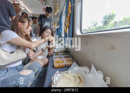 230711 -- CHONGQING, le 11 juillet 2023 -- les passagers dégustent des spécialités locales à bord du train n° 5630 de Zunyi, dans la province du Guizhou du sud-ouest de la Chine, à la municipalité de Chongqing du sud-ouest de la Chine, le 11 juillet 2023. Les trains n°5630 et 5629 sont des trains lents circulant entre Zunyi de la province de Guizhou et la municipalité de Chongqing dans le sud-ouest de la Chine. Les autorités ferroviaires locales ont organisé des marchés et des spectacles à bord, qui permettent aux villageois vivant le long de la ligne de train de vendre des marchandises aux passagers et, parallèlement, offrent aux passagers une expérience de voyage spéciale. CHINE-CHONGQING-GUIZHOU-TRAIN-MARK À BORD Banque D'Images