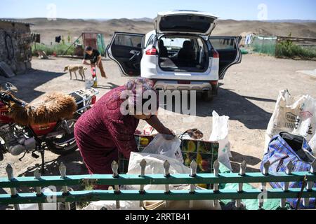 230711 -- YUMIN, le 11 juillet 2023 -- Baht Turlksi et sa petite fille Kursunak préparent des trucs pour le voyage dans les pâturages d'été dans le comté de yumin, dans la région autonome ouygur du Xinjiang du nord-ouest de la Chine, le 3 juillet 2023. Le premier jour du voyage, la route est relativement plate et les matériaux peuvent être transportés au pied de la montagne en voiture. Baht Turlksi, un éleveur de 53 ans, vit près de la majestueuse montagne Baluke, qui se trouve dans le sud du comté de yumin, dans la région autonome ouïgour du Xinjiang, au nord-ouest de la Chine. Baht signifie bonheur , ce nom porte la plus pure attente des parents pour une Bette Banque D'Images