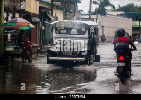 230726 -- MALABON CITY, 26 juillet 2023 -- Une jeepney traverse une zone gorgée d'eau à Malabon City, aux Philippines, le 26 juillet 2023. L'agence nationale de lutte contre les catastrophes des Philippines a déclaré mercredi qu'elle avait jusqu'à présent dénombré au moins un mort alors que le typhon Doksuri continuait de frapper le pays avec de la pluie et des vents forts. Doksuri a touché huit régions à travers l'île de Luzon et le centre des Philippines. Près de 9 000 résidents déplacés séjournent dans 107 centres d’évacuation, a ajouté le Conseil national de gestion et de réduction des risques de catastrophe. PHILIPPINES-MALABON VILLE-TYPHON DOKSURI ROUELLEXUMALI P Banque D'Images