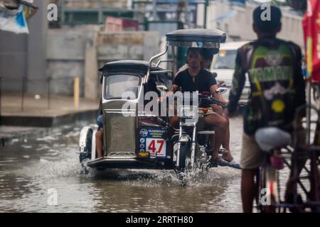 230726 -- VILLE de MALABON, 26 juillet 2023 -- des gens se promenaient dans une zone gorgée d'eau à Malabon City, aux Philippines, le 26 juillet 2023. L'agence nationale de lutte contre les catastrophes des Philippines a déclaré mercredi qu'elle avait jusqu'à présent dénombré au moins un mort alors que le typhon Doksuri continuait de frapper le pays avec de la pluie et des vents forts. Doksuri a touché huit régions à travers l'île de Luzon et le centre des Philippines. Près de 9 000 résidents déplacés séjournent dans 107 centres d’évacuation, a ajouté le Conseil national de gestion et de réduction des risques de catastrophe. PHILIPPINES-MALABON VILLE-TYPHON DOKSURI ROUELLEXUMALI PUBLIC Banque D'Images