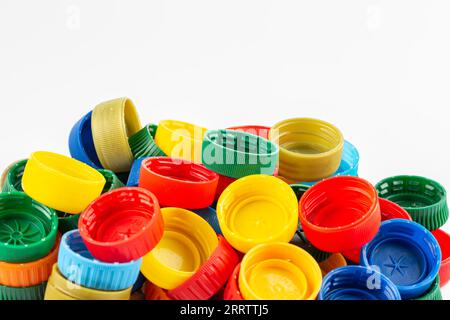 Bouchons de bouteille de différentes couleurs, excellente matière première pour le recyclage. Composition avec flacons et bouchons en plastique isolés sur du blanc. Banque D'Images