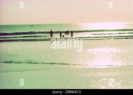 Des gens jouant dans l'eau à la plage de Kuta sur l'île de Bali Banque D'Images