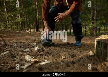 Homme âgé s'est foulé la jambe pendant un voyage de randonnée à l'extérieur dans la forêt Banque D'Images