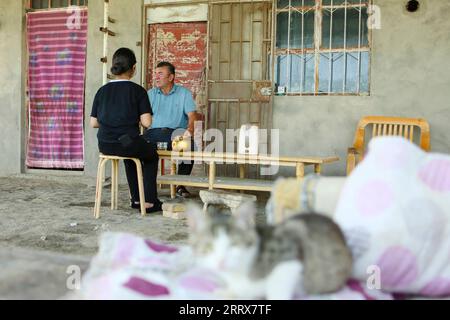 230825 -- YULI, 25 août 2023 -- Arkin Reyim discute avec sa fille pendant la pause dans le village de Bax Mali, dans le comté de Yuli, dans le nord-ouest de la Chine, dans la région autonome ouïgour du Xinjiang, le 17 août 2023. Août est le moment où Arkin Reyim prend soin des boules de coton dans sa ferme de coton de plus de 300 mu 20 hectares dans le village de Bax Mali dans le comté de Yuli. Après les semis de printemps cette année, une chute soudaine de la température en mai a presque détruit sa ferme. Grâce à ses expériences, Arkin Reyim a semé à nouveau dans le temps et a rattrapé la perte. Outre le champ de coton, Arkin Reyim plante également des cors, élève des moutons et des bœufs. Banque D'Images