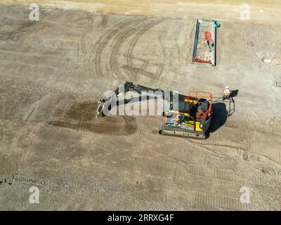 Pontyclun, pays de Galles - 7 septembre 2023 : vue par drone d'une excavatrice grattant le sol pour préparer le parking d'un nouveau supermarché dans le sud du pays de Galles Banque D'Images