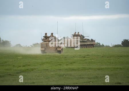Char de véhicule de combat FV510 de l'armée britannique se déplaçant à travers un champ d'herbe lors d'un exercice militaire Banque D'Images