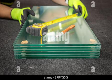 Usine de verre, verre épais broyé reposant sur la table en verre, prêt à être emballé pour le client, ruban à mesurer et coupe-verre pour couper le verre, Glazier' Banque D'Images