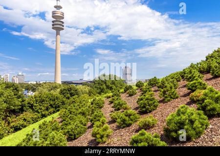 Tour de télévision et bâtiment du siège de BMW, vue depuis le parc olympique, Munich, Allemagne. Paysage avec des repères de la ville de Munchen sur fond de ciel. Vert con Banque D'Images