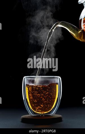 thé chaud versé de théière dans une tasse en verre Banque D'Images