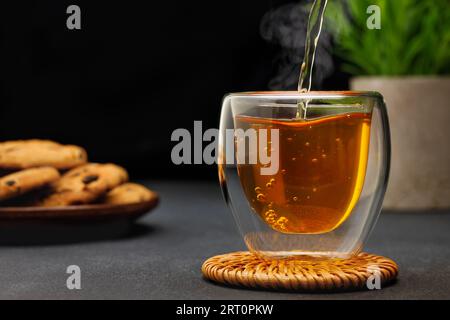 thé chaud coulant de théière dans une tasse en verre sur la table Banque D'Images