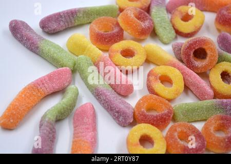 Bonbons colorés beaux et lumineux de bonbons pour enfants sous la forme de vers de terre sucrés de différentes couleurs, beignets américains, sucettes. Banque D'Images