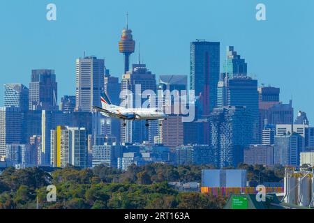 Les gratte-ciel de Sydney, en Australie, avec un avion Rex Regional Express descendant vers l'aéroport de Sydney. Banque D'Images