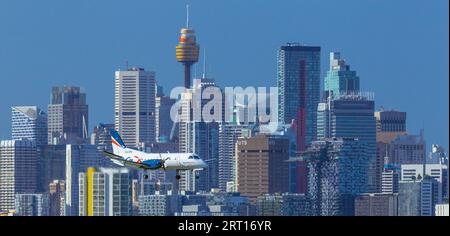 Les gratte-ciel de Sydney, en Australie, avec un avion Rex Regional Express descendant vers l'aéroport de Sydney. Banque D'Images