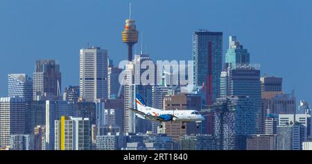 Les gratte-ciel de Sydney, en Australie, avec un avion Rex Regional Express descendant vers l'aéroport de Sydney. Banque D'Images