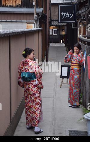 Deux jeunes filles japonaises vêtues de kimono prenant des photos dans le quartier de Gion, l'un des quartiers de geisha les plus exclusifs et les plus connus de Kyoto, au Japon Banque D'Images