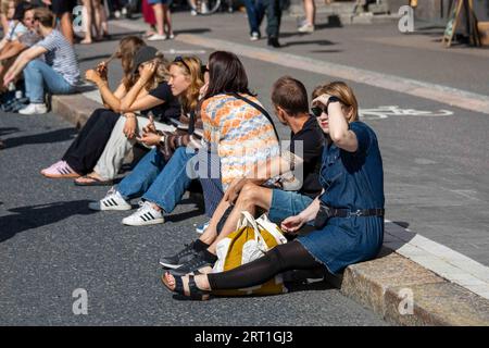 Des jeunes assis sur un trottoir au Kallio Block Party 2023 à Helsinki, Finlande Banque D'Images