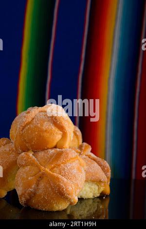 Pain mort sur la table en verre noir avec sérape coloré en arrière-plan. Dessert typique du jour des morts. Banque D'Images