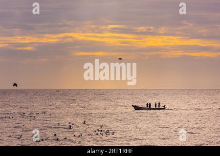 Petit bateau de pêche avec les pêcheurs sur la mer près de Pondichéry en Inde du Sud pendant le lever du soleil Banque D'Images