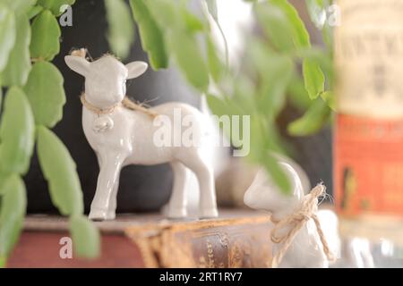Gros plan sur deux petites figurines d'agneau pascal de pâques faites de chine blanche se tenant sur un placard dans le salon avec accent sur l'agneau gauche Banque D'Images