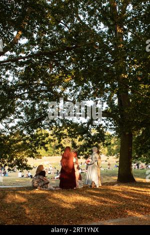 Londres, Royaume-Uni. . 9 septembre 2023. Les femmes en vêtements africains trouvent refuge à l'ombre sous les arbres de Greenwich Park tandis que de plus en plus de Londoniens prennent le soleil en arrière-plan. Cristina Massei/Alamy Live News Banque D'Images