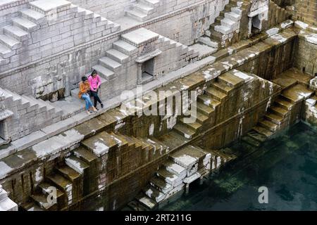 Jodhpur, Inde, 8 décembre 2019 : deux filles assises sur les marches du stepwell Toorji Ka Jhalra dans le centre historique de la ville Banque D'Images