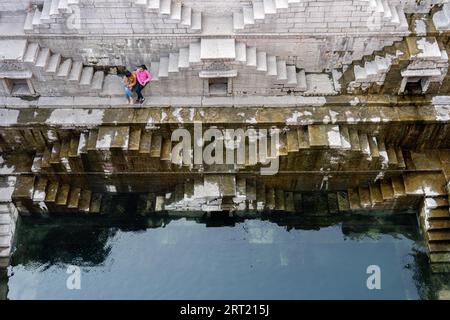 Jodhpur, Inde, 8 décembre 2019 : deux filles assises sur les marches du stepwell Toorji Ka Jhalra dans le centre historique de la ville Banque D'Images