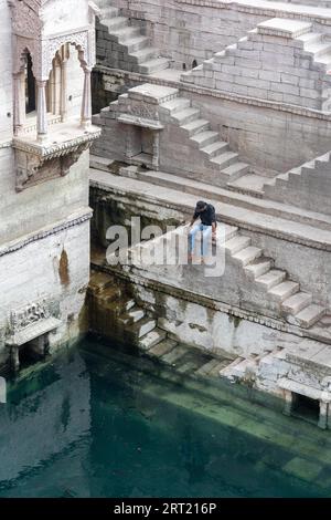 Jodhpur, Inde, 8 décembre 2019 : un homme assis sur les marches du stepwell Toorji Ka Jhalra dans le centre historique de la ville Banque D'Images