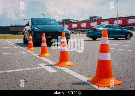 Voiture moderne sur piste d'essai, concentrez-vous sur les cônes de circulation. Femme passant un test de conduite. Test de conduite de l'école de conduite, cours de conducteur, concept d'examen Banque D'Images