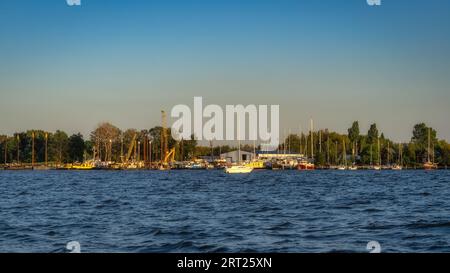 Chantier naval et port de Szczecin Dabie marina avec yachts amarrés et bateaux au coucher du soleil. Grues et hangars en arrière-plan, Pologne Banque D'Images