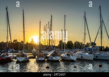 Beau coucher de soleil avec des rayons de soleil illuminant des yachts de luxe et des bateaux amarrés dans une rangée à Szczecin Dabie marina, Pologne Banque D'Images