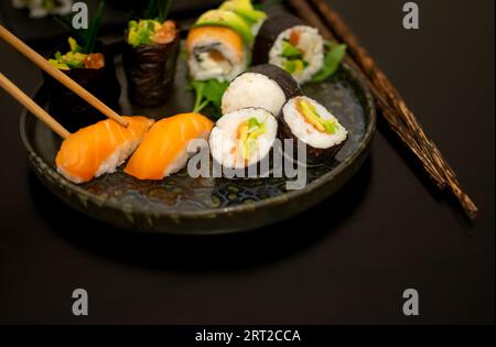 Baguettes prenant Sushi Nigiri de luxe, plaquées de manière créative avec Gunkan et Uramaki Banque D'Images