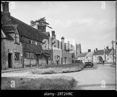 High Street, Steeple Ashton, Wiltshire, 1932. Une vue vers le nord le long des maisons sur la High Street à Steeple Ashton avec la tour de l'église St Mary au-delà. Banque D'Images