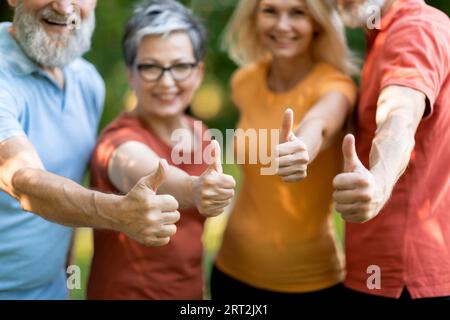Heureux Senior People dans Sportswear montrant Thumbs Up à la caméra, debout à l'extérieur Banque D'Images
