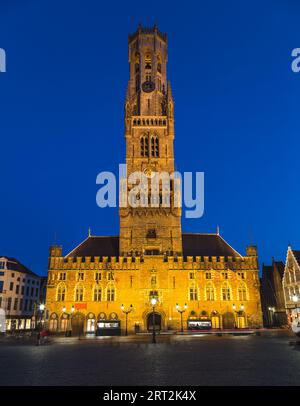 Vue du beffroi de Bruges au crépuscule depuis Grote Markt (Grande place du marché) avec un ciel bleu en arrière-plan. Banque D'Images