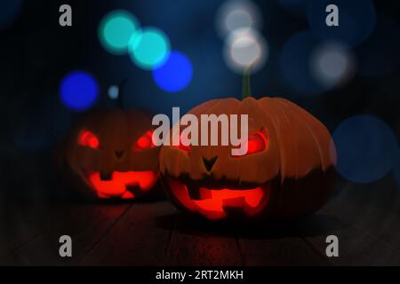 Une citrouille avec un visage sculpté et effrayant. Concept de vacances Halloween. Halloween citrouille tête jack o lanterne avec fond de feu brûlant, table en bois avec Banque D'Images