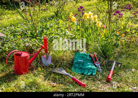 Jardinage avec râteau, ciseaux, arrosoir et gants dans un jardin au printemps, jardinage avec râteau, ciseaux, arrosoir et gants dans un jardin Banque D'Images