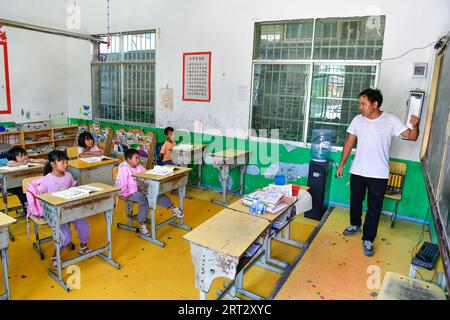 (230910) -- GUIDING, 10 septembre 2023 (Xinhua) -- lu Chengwen (1e R) enseigne les mathématiques aux élèves de première année au point d'enseignement de Yanjiao dans le canton de Yanshan, dans le comté de Guizhou, dans le sud-ouest de la Chine, dans la province du Guizhou, 6 septembre 2023. Yanjiao point d'enseignement est une «micro école primaire» située dans une zone plate parmi les montagnes dans le sud-ouest de la Chine Guizhou. Lu Chengwen est le seul enseignant ici avec 28 élèves préscolaires et 6 élèves de première année. En 2012, lu, qui venait de sortir de l'université, choisit d'enseigner au point d'enseignement éloigné de Yanjiao. Élèves d'âge préscolaire, élevés dans le village montagneux du Miao Banque D'Images