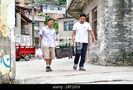 (230910) -- GUIDING, 10 septembre 2023 (Xinhua) -- lu Chengwen (à droite) et le bricoleur Pan Delu ramènent les ingrédients des repas nutritifs des élèves d'un marché du comté de Guizhou, dans le sud-ouest de la Chine, dans la province du Guizhou, le 7 septembre 2023. Yanjiao point d'enseignement est une «micro école primaire» située dans une zone plate parmi les montagnes dans le sud-ouest de la Chine Guizhou. Lu Chengwen est le seul enseignant ici avec 28 élèves préscolaires et 6 élèves de première année. En 2012, lu, qui venait de sortir de l'université, choisit d'enseigner au point d'enseignement éloigné de Yanjiao. Élèves d'âge préscolaire, élevés dans le villag montagneux Banque D'Images