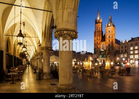 Ville de Cracovie de nuit en Pologne, place principale dans la vieille ville avec St. Mary Church depuis l'arcade de la salle de coth (Sukiennice) Banque D'Images