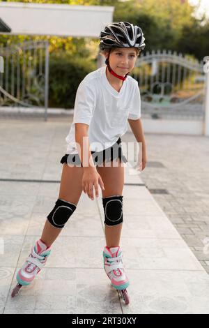 Jeune patineur heureux portant un casque de sécurité essayant des activités de plein air passionnantes Banque D'Images