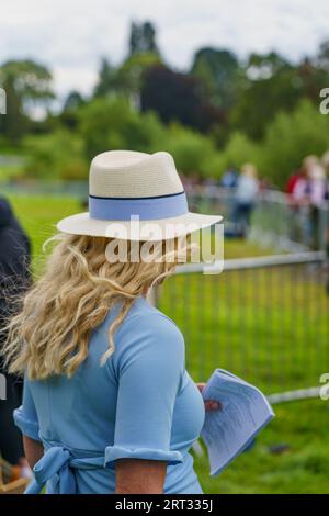 Femme aux longs cheveux blonds au Ripley show, North Yorkshire, Angleterre ; portant un Orford fedora avec un ruban bleu clair et une robe qui correspond. Banque D'Images