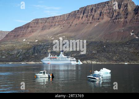 Ilulissat, Groenland, 06 juillet 2018 : un grand bateau de croisière et des bateaux de pêche ancrés dans le port de Qeqertarsuaq Banque D'Images