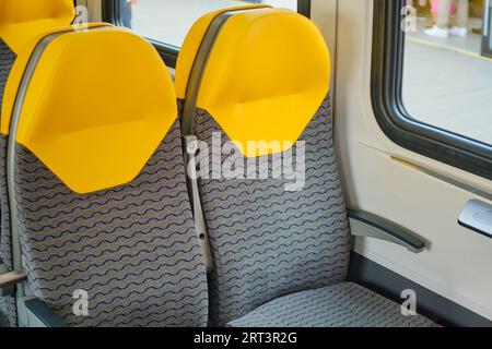 Gros plan d'une paire de sièges de train en caoutchouc jaune et gris Banque D'Images