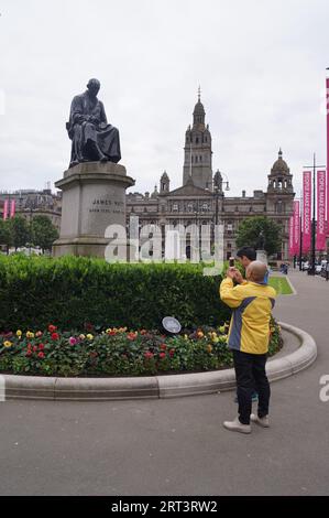 Glasgow, Écosse (Royaume-Uni) : un touriste prend une photo de la statue de James Watt à George Square Banque D'Images