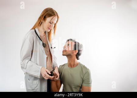 Médecin utilisant un oxymètre de pouls sur le doigt d'un patient asiatique. Femme rousse caucasienne. Homme asiatique d'Inde. Banque D'Images