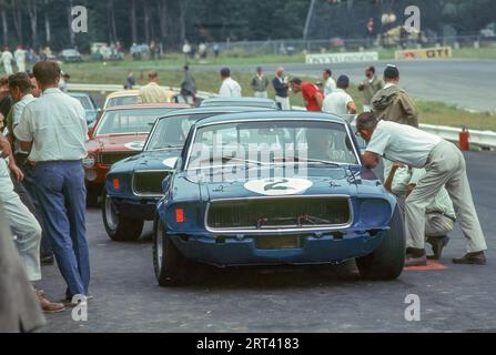 Voitures alignées dans les stands pour la course Watkins Glen Trans Am 1968 à Watkins Glen NY USA. 1e voiture est Dan Gurney dans une Shelby Racinbg Ford Mustang, n'a pas fini Banque D'Images