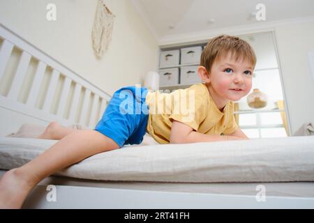 Le bébé risque de tomber en jouant sur le lit. Enfant âgé de deux ans (garçon de deux ans) Banque D'Images